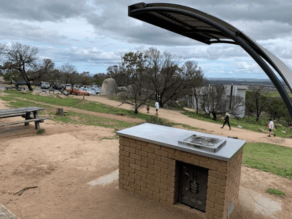 Family-walking-toward-Big-Rock-in-You-Yangs-Regional-Park-with-granite-boulders-and-scenic-views.