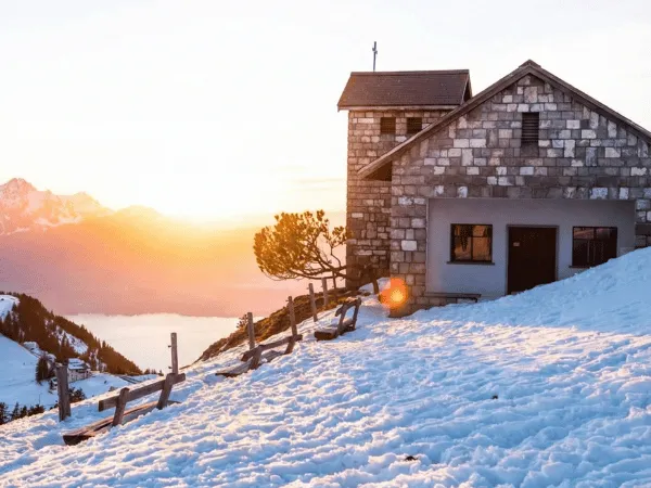 Swiss mountain chalet at sunrise surrounded by snow during winter