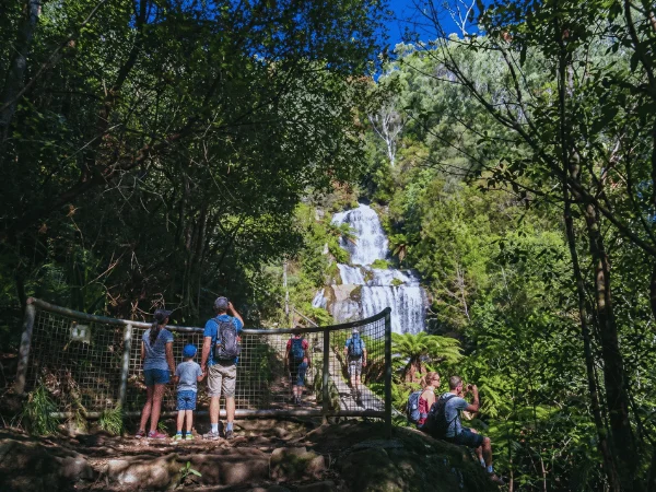 People standing near Fainter Falls admiring the waterfall and forested surroundings.
