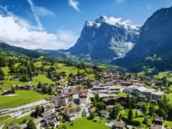 Grindelwald Switzerland alpine village with green meadows, wooden chalets, and the Eiger mountain in the background 2