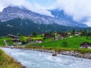 Grindelwald Switzerland alpine village with green meadows, wooden chalets, and the Eiger mountain in the background 3