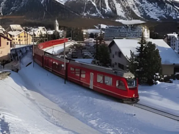 Red train traveling through Celerina village in the Engadin Valley Switzerland