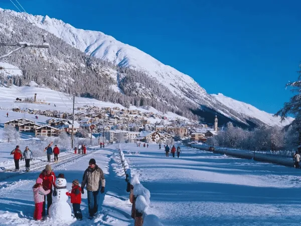 People enjoying winter activities in Samedan surrounded by snow-covered mountains