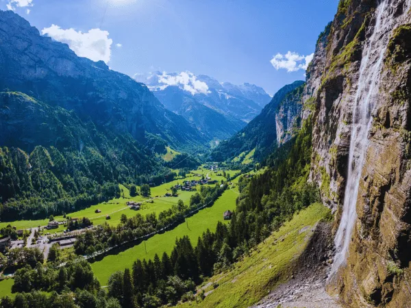 waterfall flowing down cliffs into the green lauterbrunnen valley in switzerland