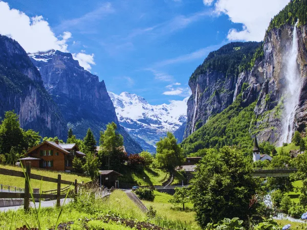 lauterbrunnen village with traditional swiss chalets and waterfall flowing from alpine cliffs