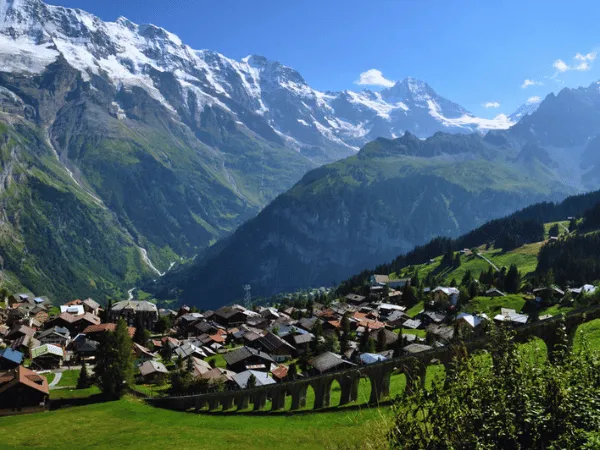 panoramic alpine view of mürren switzerland village with green meadows and snow-capped mountains