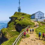 hikers-walking-path-at-rigi-kulm-summit-with-alpine-views-and-hotel-in-background