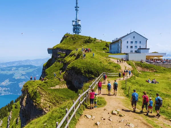 hikers-walking-path-at-rigi-kulm-summit-with-alpine-views-and-hotel-in-background