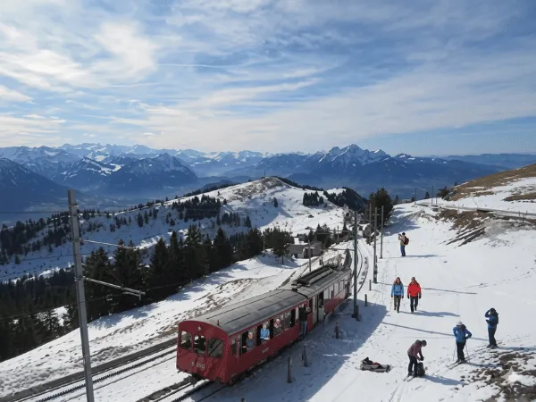 red-rigi-cogwheel-train-descending-snow-covered-mountain-with-alps-in-background
