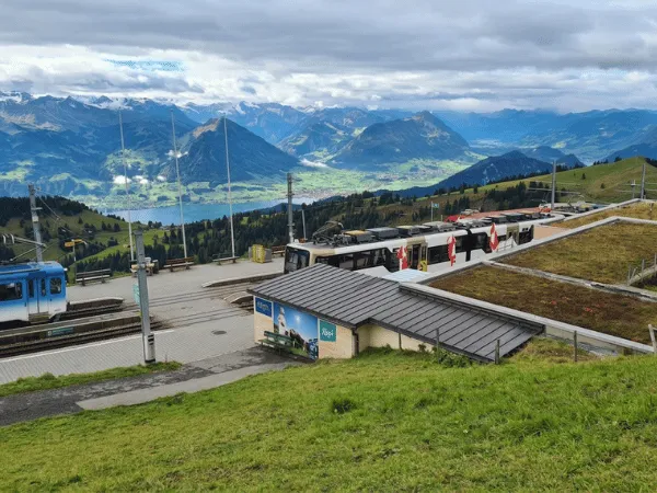 rigi-kulm-mountain-railway-station-with-cogwheel-trains-and-alpine-mountain-backdrop