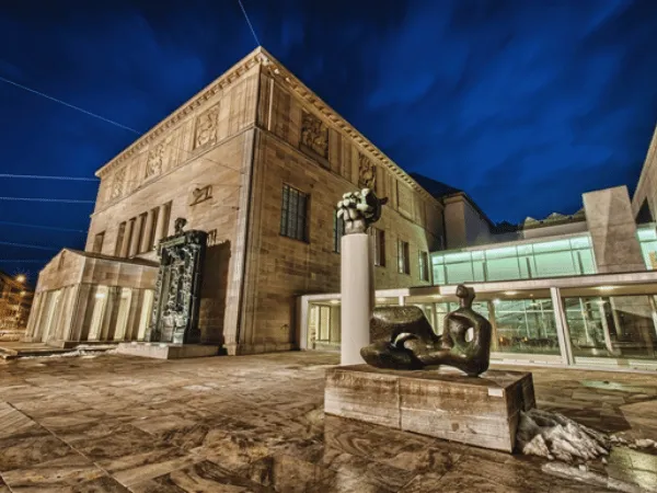 kunsthaus-zurich-illuminated-at-night-with-bronze-sculptures-in-the-foreground