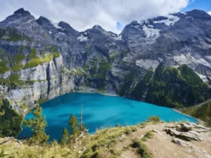 elevated hiking trail viewpoint above oeschinensee kandersteg showing vivid turquoise lake surrounded by dramatic limestone walls and glaciated peaks switzerland