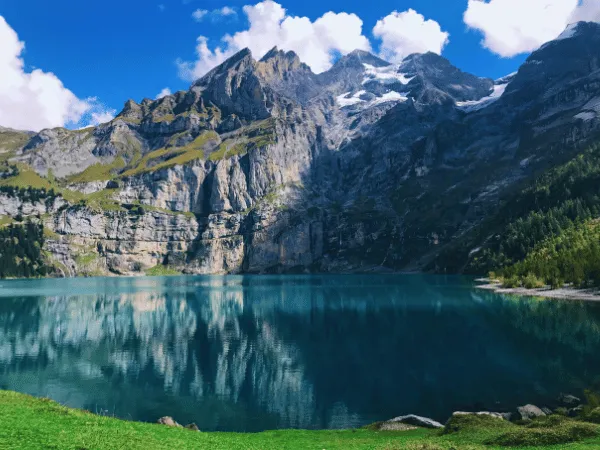 oeschinensee kandersteg clear turquoise water reflecting limestone cliff walls and alpine peaks on a sunny summer day switzerland