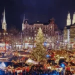 aerial-night-view-of-zurich-christmas-market-with-festive-lights-and-grossmunster-cathedral-towers