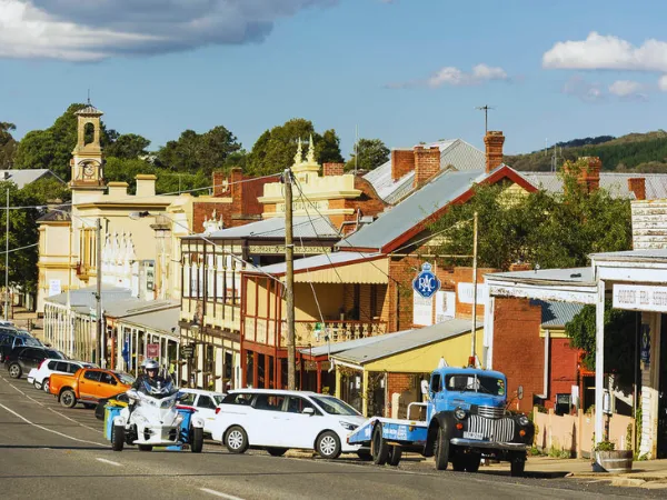 Historic gold rush era buildings lining the main street of Beechworth Victoria with vintage vehicles and a clock tower in the background
