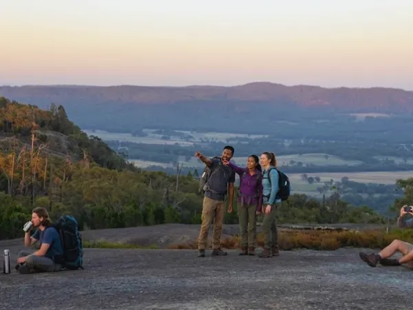 Group of hikers enjoying sunset views from the granite summit of Mt Pilot Lookout Walk, Chiltern Victoria