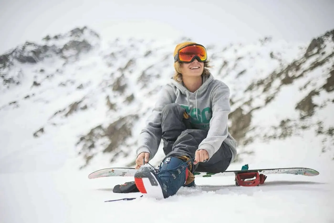 lessexplore-snowboarder-strapping-in-winter-mountains