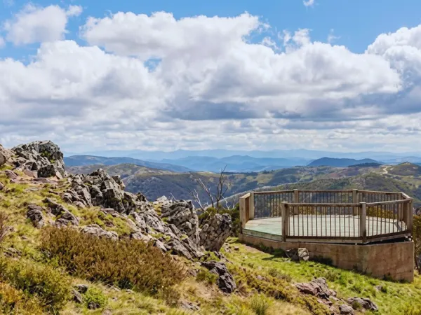 Wooden octagonal viewing platform at Mt Higgi Lookout overlooking the Victorian Alps with rocky outcrops and cloudy sky