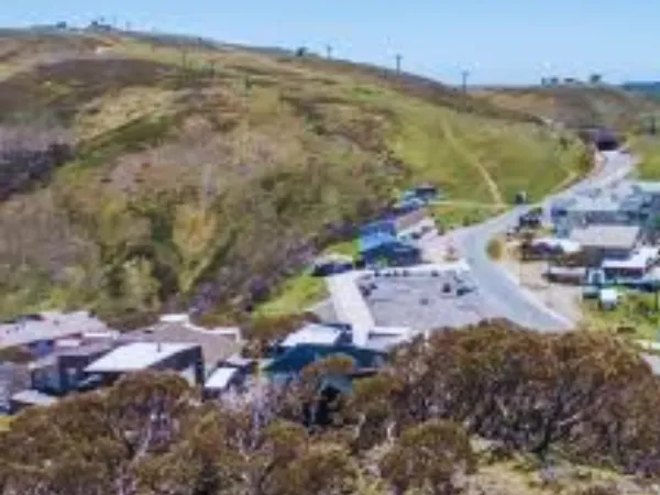Aerial view of Mt Hotham Alpine Resort village surrounded by alpine hills and ski lifts in summer