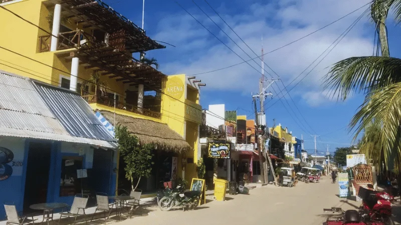 Colorful storefronts along a sandy street in Isla Holbox town center
