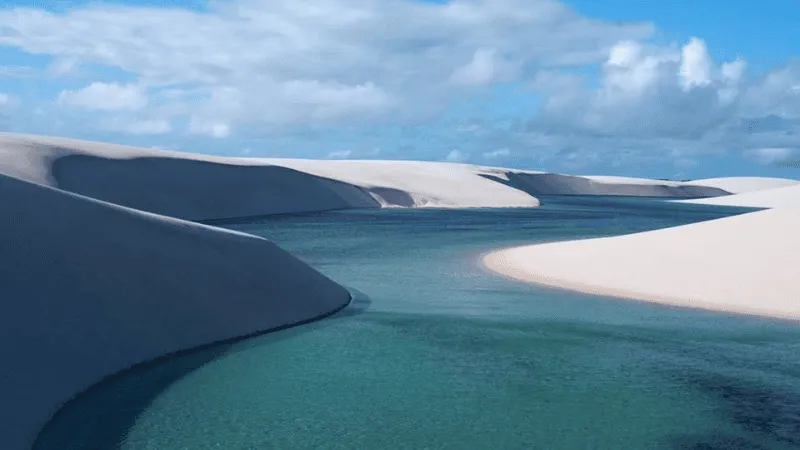 Teal lagoon winding between white sand dunes in Brazil