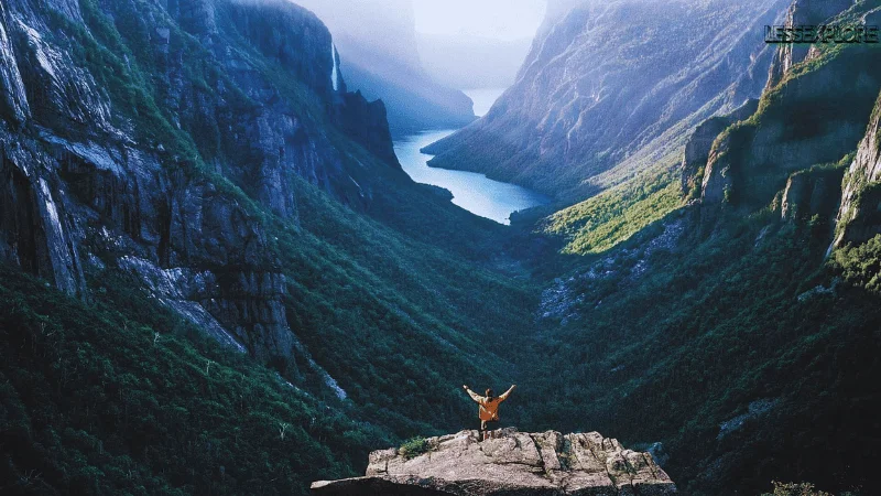 Hiker standing on a cliff edge overlooking the fjord valley in Gros Morne National Park