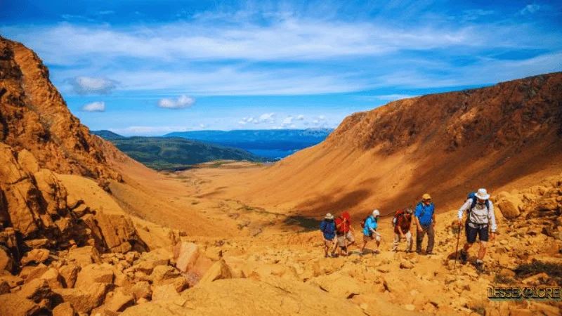 Hikers walking through the orange rocky terrain of the Tablelands in Gros Morne National Park